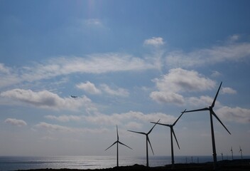 Avión, aerogeneradores y cielo con nubes