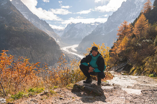 Man squatting in front of Mer de Glace glacier on sunny day, Chamonix, France