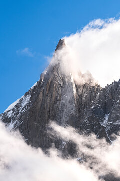 Aiguille du Dru mountain surrounded by clouds on sunny day, Chamonix, France