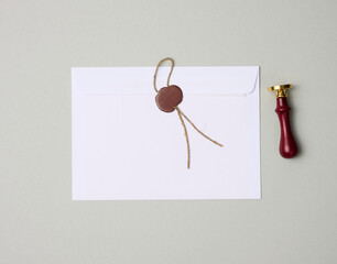sealed white envelope with brown wax seal on gray background, flat lay