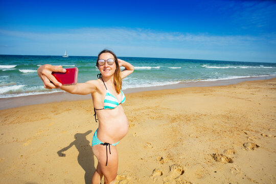 Pregnant woman on sea beach make selfie with phone