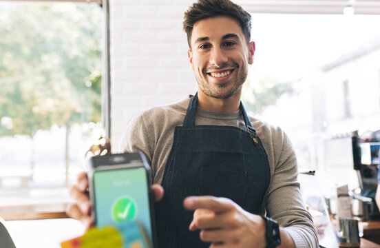 Waiter pointing at credit card reader screen in cafe