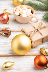 Christmas or New Year composition. Decorations, box, balls, fir and spruce branches, cup of coffee, on a white wooden background. Side view.