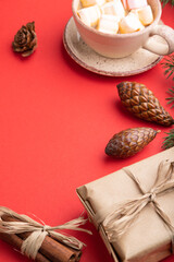 Christmas or New Year composition. Decorations, cones, fir and spruce branches, cup of coffee, on a red background. Side view, copy space.