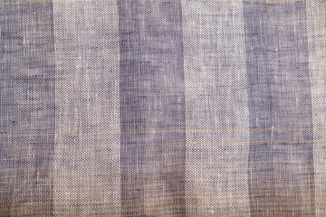 Fragment of smooth brown and violet linen tissue. Top view, natural textile background.