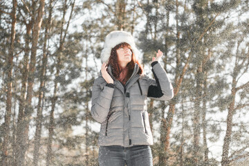 Winter fun. Woman plays throwing snow with arms up open in freedom enjoying cold season. Happy and joyful concept.