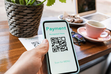 Woman with QR code paying through mobile phone at cafe