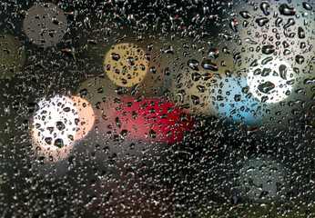 colorful diffuse unsharp lights behind glass window with rain drops
