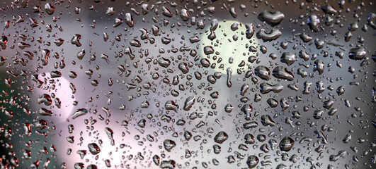 colorful diffuse unsharp lights behind glass window with rain drops
