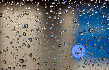 colorful diffuse unsharp lights behind glass window with rain drops