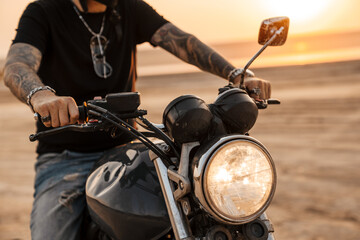 Mature man wearing black t-shirt with tattoo posing on motorbike