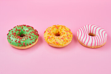 Fototapeta na wymiar Doughnut with multicolored glaze on trendy pink background. Donut are traditional sweet pastries.