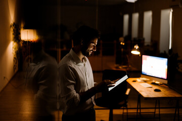 White bearded man working with tablet computer in evening