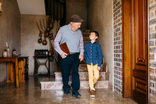 Grandson holding grandfather hand at home