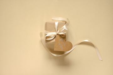 A gift wrapped in natural paper, a satin ribbon and a heart-shaped label (with the words 