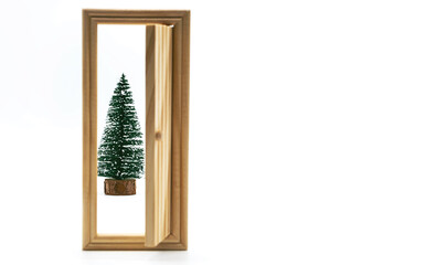 Christmas tree behind the open wooden door, on white. Creative, minimal winter holidays concept.