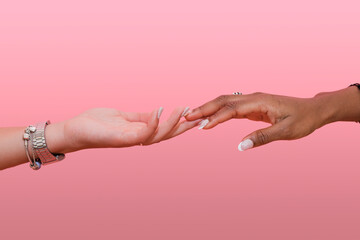 Lesbian women reaching for each other against pink background