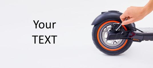 Space for text. Hand repairing electrical scooter on white background. Repair service for fixing electrical escooters. © wertinio
