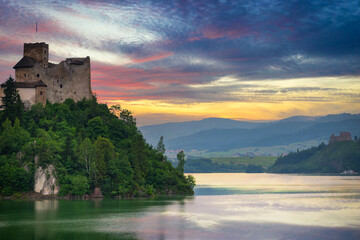 Naklejka na ściany i meble Medieval Dunajec Castle in Niedzica with a reflection in the Czorsztyn Lake at sunset. Poland
