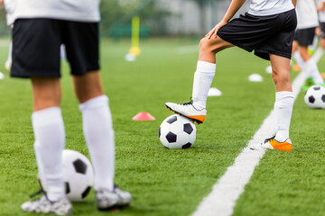 Football Training Unit. Soccer Players in Black and White Football Clothing Kicking Classic Soccer Balls. Soccer Grass Practice Pitch. School Soccer Training Session