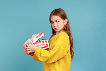 Side view of little girl opens gift box, expresses sadness, celebrates holiday, disappointed of...