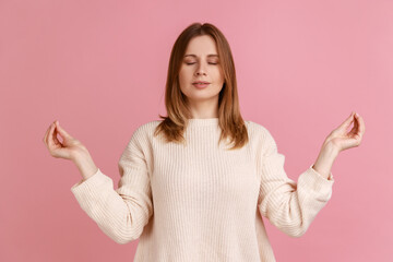 Portrait of blond woman closing eyes and holding hands up in mudra gesture, meditating, yoga...