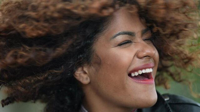 Carefree latina black woman shaking hair and smiling at camera