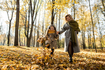 Playful girl and mother having fun in autumn park