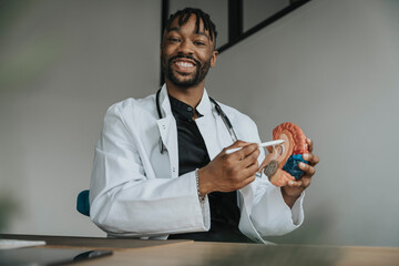 Smiling doctor with digitized pen pointing at anatomical brain model in office