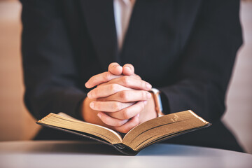 focus on woman's hand While praying for Christianity with blurry body background, casual woman prays with her hands with scriptures.