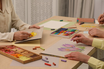 Artists drawing with soft pastels and pencils at table indoors, closeup