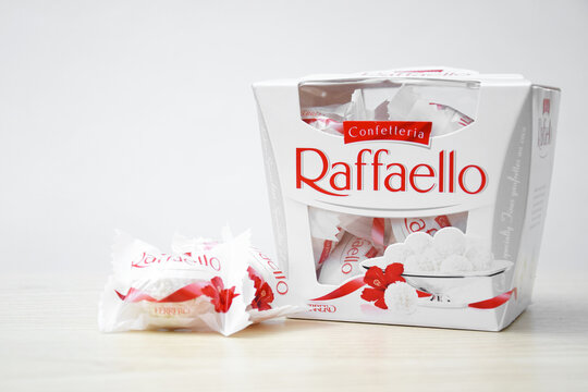 Raffaello sweets on a light wooden table and white background.
