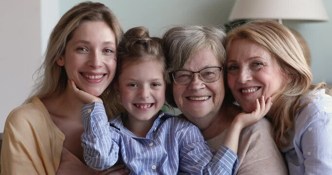 Cute little girl cuddle with mom old granny elderly great grandma touch faces of beloved relatives with affection. Family dynasty 4 happy loving diverse age females look at camera with healthy smiles