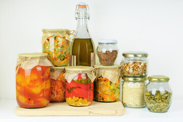 Fermented preserved vegetarian food concept. Variety of vegetarian products and fermented foods in glass jars for storage on white wooden table. Probiotics foods in balanced dieting food.