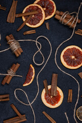 Autumn dark background with candied, dried oranges, cinnamon and spices with red autumn leaves and decorative cord or twine on a black matte background. Flat top view.