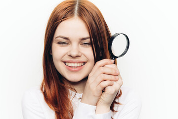 red-haired woman in a white shirt with a magnifying glass in her hands searching