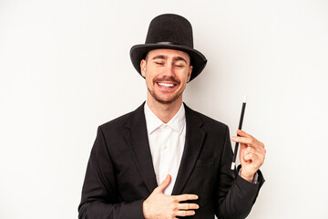 Young caucasian wizard man holding a wand isolated on white background laughing and having fun.