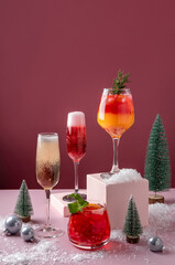 Festive citrus cocktails on podiums. Assortment of fresh Christmas drinks. Pink and red sangria...