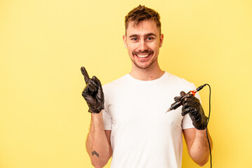 Young caucasian tattoo maker man isolated on yellow background pointing to the side