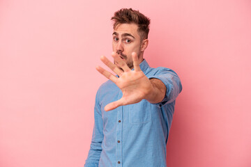 Young caucasian man isolated on pink background being shocked due to an imminent danger
