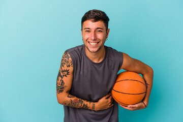 Young caucasian man playing basketball isolated on blue background  laughing and having fun.