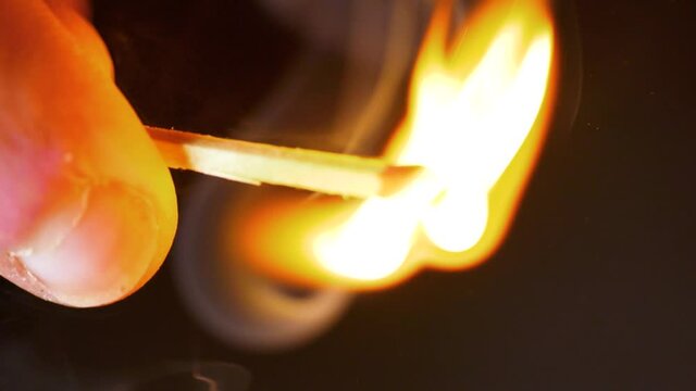 HD Super slow motion cinematic macro shot of a match being lit, in a dark room.
