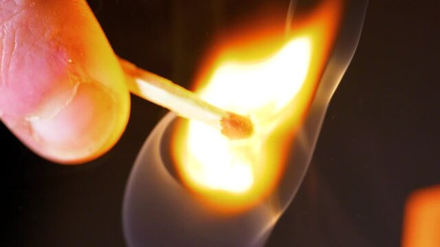 HD Super slow motion cinematic macro shot of a match being lit, in a dark room.
