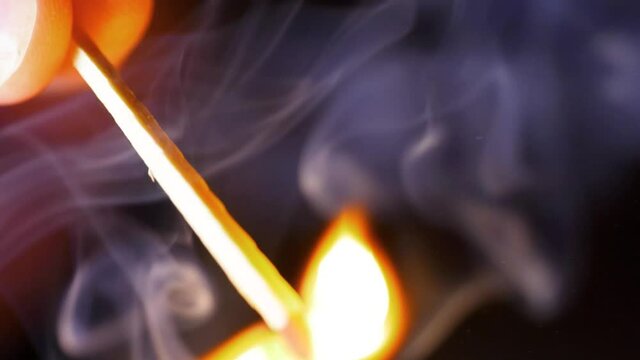 HD Super slow motion cinematic macro shot of a match being lit, in a dark room.