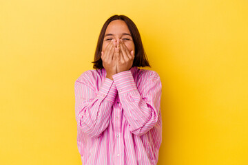 Young mixed race woman isolated on yellow background laughing about something, covering mouth with hands.