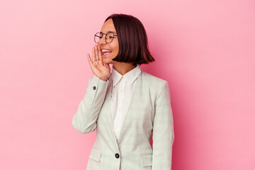 Young mixed race woman wearing a green suit isolated on pink background shouting and holding palm near opened mouth.