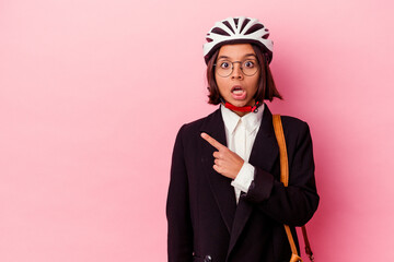Young business mixed race woman wearing a bike helmet isolated on pink background pointing to the side