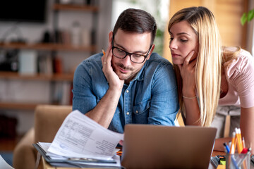 Worried young couple checking bills