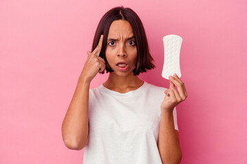 Young mixed race woman holding a compress isolated on pink background pointing temple with finger, thinking, focused on a task.