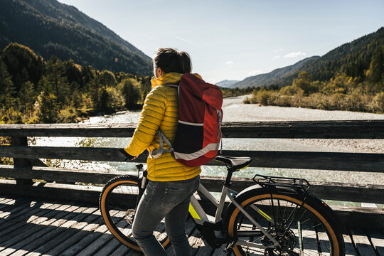 Woman with backpack and mountain bike on bridge